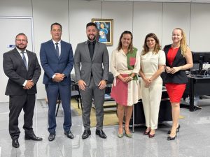 Seis pessoas posando para foto lado a lado. São três homem usando terno e três mulheres usando roupas formais.