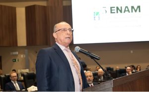 Homem de terno azul marinho fala ao microfone