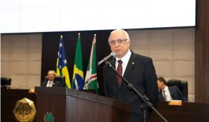 Homem de terno preto fala ao microfone