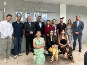 Doze pessoas posando para foto. Ao fundo, cinco homens e três mulheres de pé e lado a lado. À frente, três mulheres sentadas.