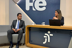 Um homem sentado em uma poltrona e uma mulher numa bancada. Eles olham para a câmara. Ao fundo, a logomarca do programa hora extra. Embaixo da bancada, a logomarca da Justiça do Trabalho