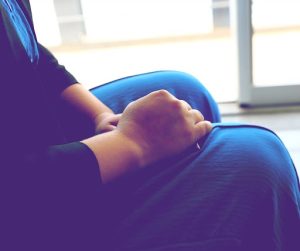 imagem ilustrativa mostra parte do corpo de uma mulher sem mostrar o rosto, com as mãos postas sobre as pernas.