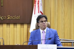 Homem de terno sentado falando ao microfone