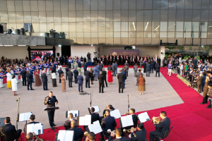 foto mostra evento de cima com orquestra e pessoas perfiladas