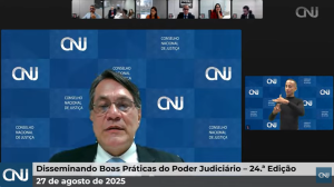 Homem de terno e óculos falando em uma reunião virtual com outros cinco participantes. Atrás, um plano de fundo com a denominação do CNJ. Na legenda da imagem, a escrita "Disseminando Boas Práticas do Poder Judiciário  - 24ª Reunião. 27 de agosto de 2025." 