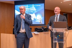 Dois homens de terno apresentam palestra no auditório do TRTGO