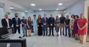 Uma fotografia de um grupo de treze pessoas em pé em um escritório. A maioria das pessoas está vestindo roupas formais.