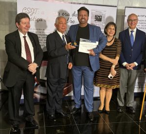 Foto mostra cinco pessoas lado a lado, sendo que a do meio segura um certificado