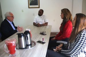 imagem mostra o padre Geovani dos Santos Pereira ao centro conversando com o desembargador Welington Peixoto e equipe