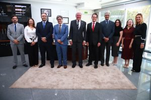 Várias pessoas em pé usando roupas formais num sala fechada.