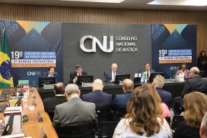 Solenidade em um auditório com logomarco do Conselho Nacional de Justiça ao fundo. 