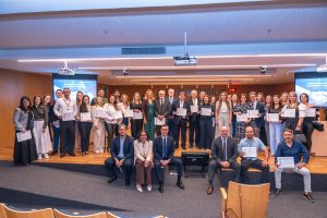 Grupo de pessoas estão no palco com seus certificados em mãos