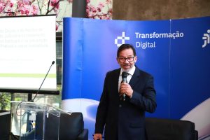 Desembargador Antônio Gomes de Vasconcelos fala ao microfone. Ele veste terno escuro e usa óculos