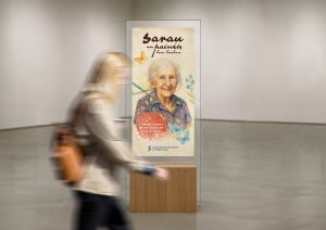 Cartaz da poetiza Cora Coralina e uma pessoa passando