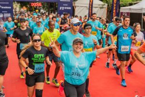 Imagem de atletas durante corrida. Eles estão usando roupas esportivas, com uma camiseta azul claro.