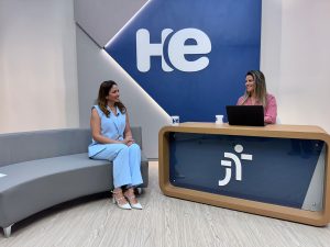 
Uma mulher sentada em uma poltrona e um mulher numa bancada. Elas olham para a câmara. Ao fundo, a logomarca do programa hora extra. Embaixo da bancada, a logomarca da Justiça do Trabalho