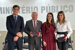 Quatro pessoas, lado a lado, posando para foto. São duas mulheres e dois homens. Eles usam roupa social e estão sorrindo para a foto.