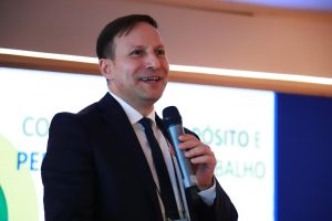 Homem segurando microfone durante palestra.