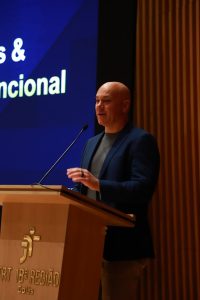 Homem de blazer fala ao microfone