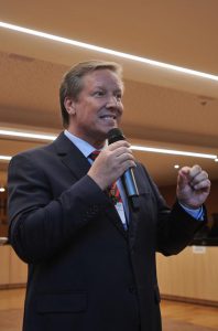 Homem de pele e cabelos claros, falando ao microfone