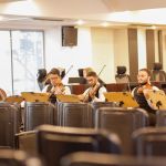 Músicos se apresentando com flauta, violinos e violoncelo